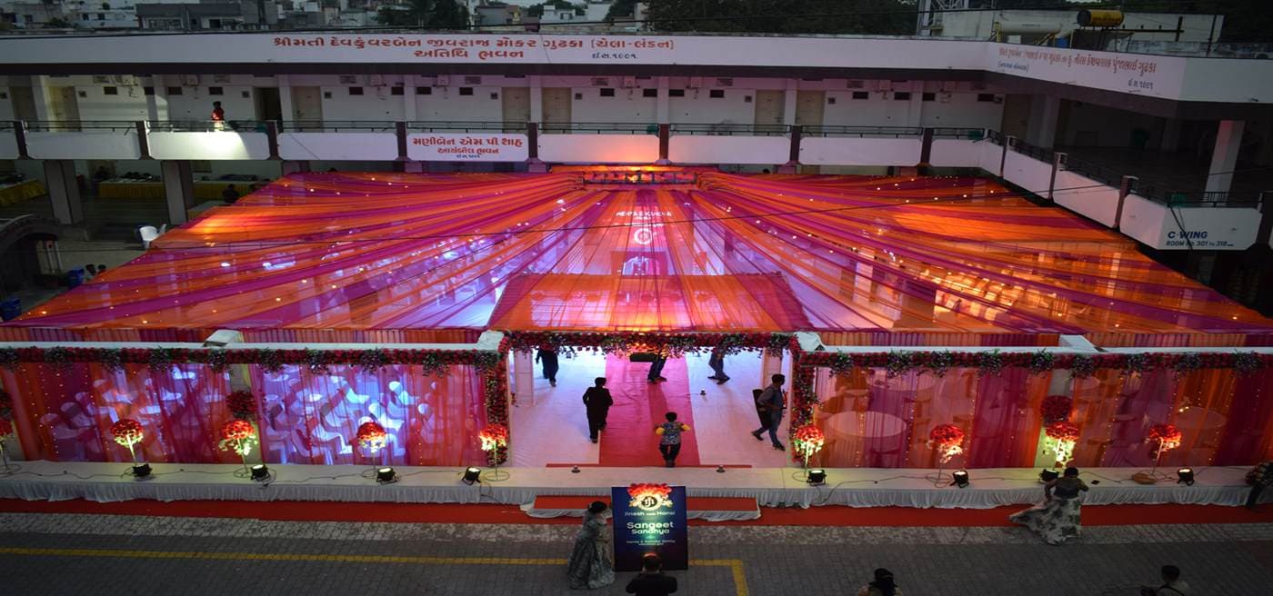 A large mandap and stage installation built by Anjan Enterprise, lit for an evening event